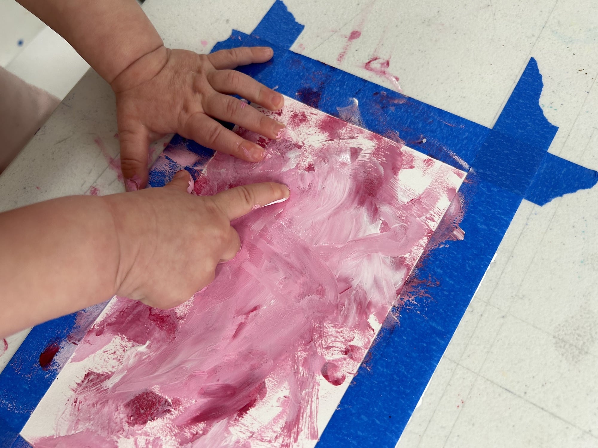 baby hands playing in pink paint 